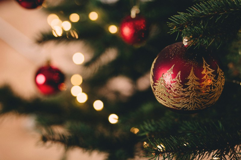 freestocks–Qf9JKLysUg-unsplash Close-up of decorated Christmas tree with red and gold ornaments and warm lights.