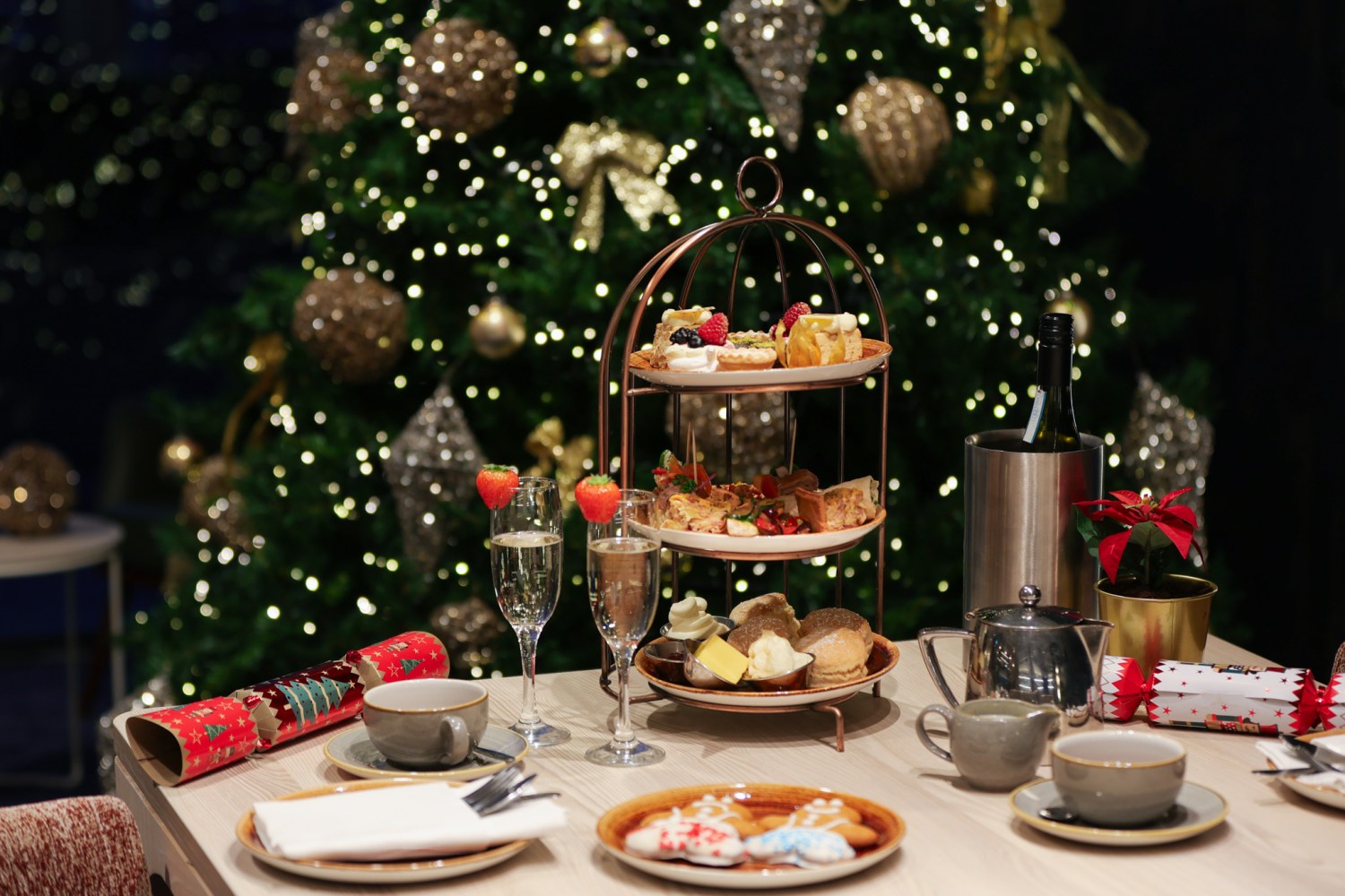 Festive table with tiered snacks, drinks, and a decorated Christmas tree in the background.