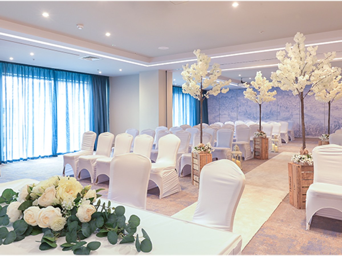 Elegant wedding venue with white chairs, floral centerpieces, and decorative trees at Sheraton Athlone Hotel