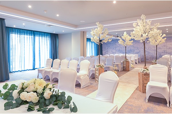 Elegant wedding venue with white chairs, floral centerpieces, and decorative trees at Sheraton Athlone Hotel