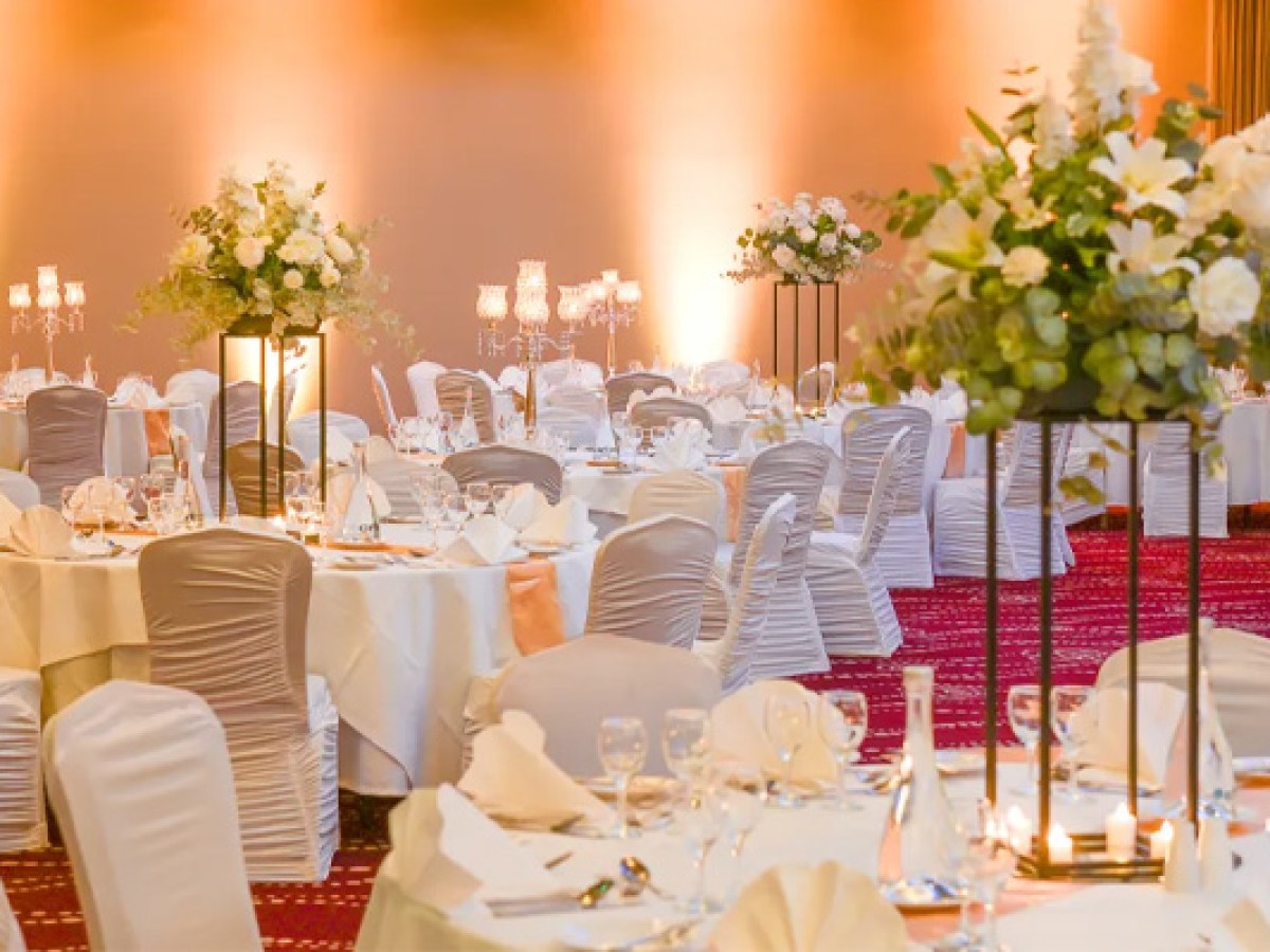 Elegant banquet hall with round tables, white chairs, and floral centerpieces all set up for Sheraton Athlone Hotel wedding
