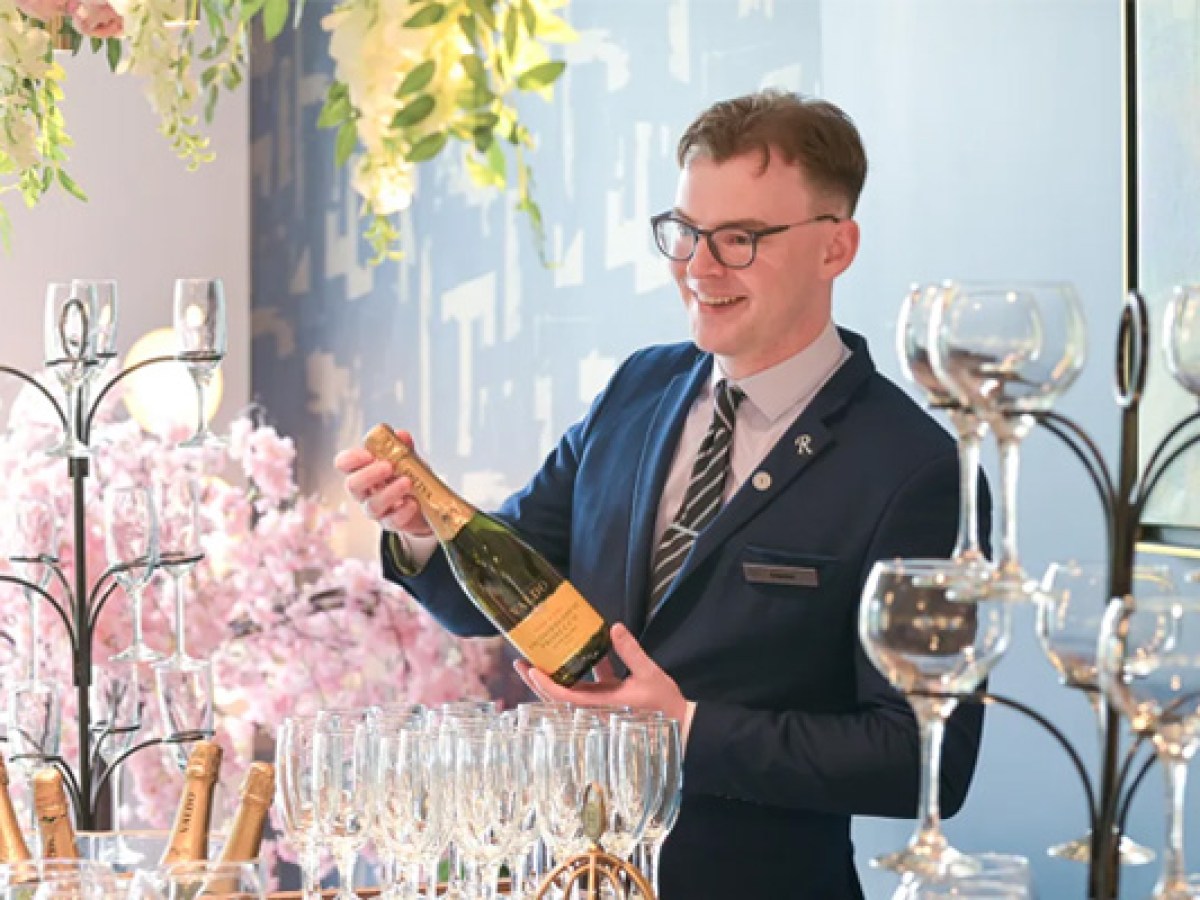 Man smiling, holding champagne bottle near stacked glasses during Sheraton Athlone wedding drinks reception