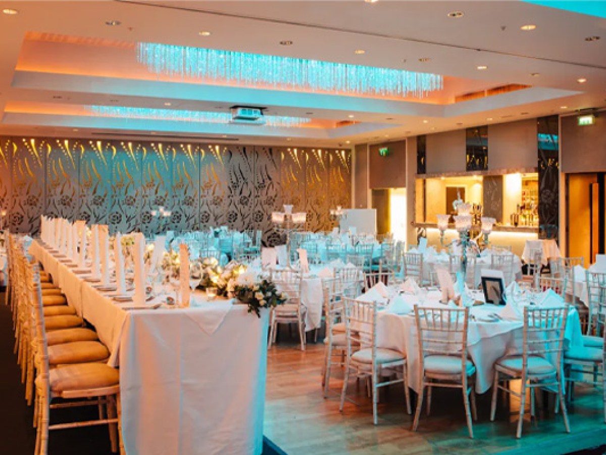 Elegant banquet hall with decorated tables and white chairs set for a wedding at the Sheraton Athlone Hotel
